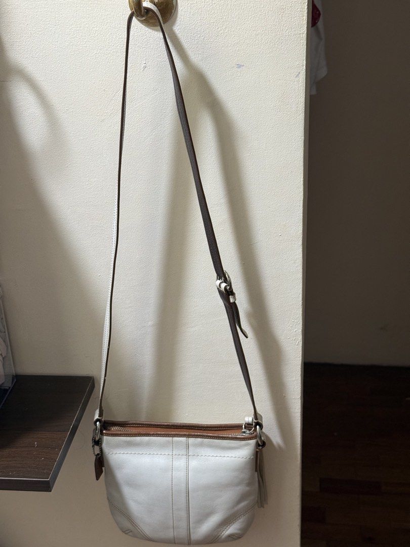 Coach New York Leather Shoulder Bag (Category: Luxury Bags & Wallets) located in Marikina City. Submitted by stuffs23 (Listing ID 1440594615, Image 2). Description: - Authentic Coach New York white leather shoulder bag - Stylish brown leather trim and adjustable strap - Adorable small tassels on the front for a touch of flair - Secure zipper closure to keep your belongings safe - Convenient interior pocket for organization - Ideal for everyday us