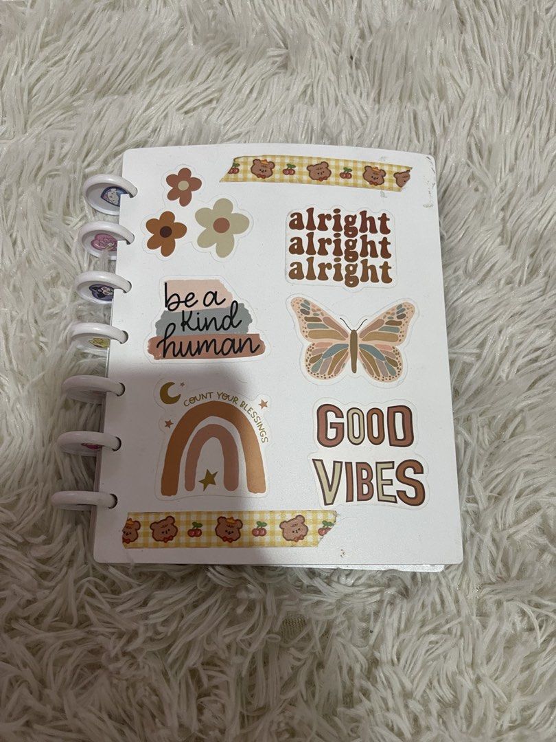 Cute Mini Notebook with Stickers & Photo Sleeves (Category: Stationery & School Supplies) located in Paranaque City. Submitted by mystic_random_vault (Listing ID 1440671352, Image 1). Description: White mini notebook or photo album. Decorated with cute stickers like flowers, rainbows, butterflies, and positive quotes. Also has some anime character stickers on the back. Comes with clear plastic sleeves inside to hold photos or cards. Great for jou