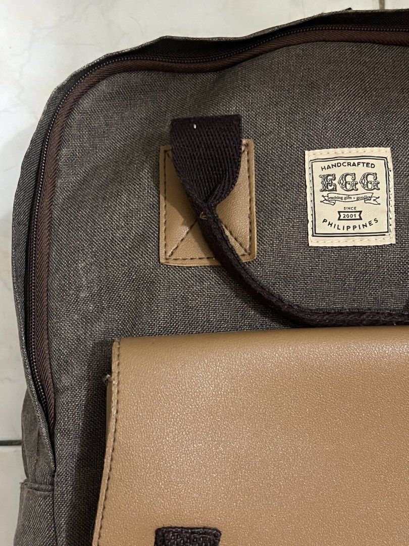 EGG Marcus Backpack (Category: Backpacks) located in Malabon City. Submitted by rika_26 (Listing ID 1440615409, Image 2). Description: Color: Dark gray with beige/tan accents > Canvas-like material with leather-style front pocket > Adjustable straps and sturdy handles RFS: Decluttering .