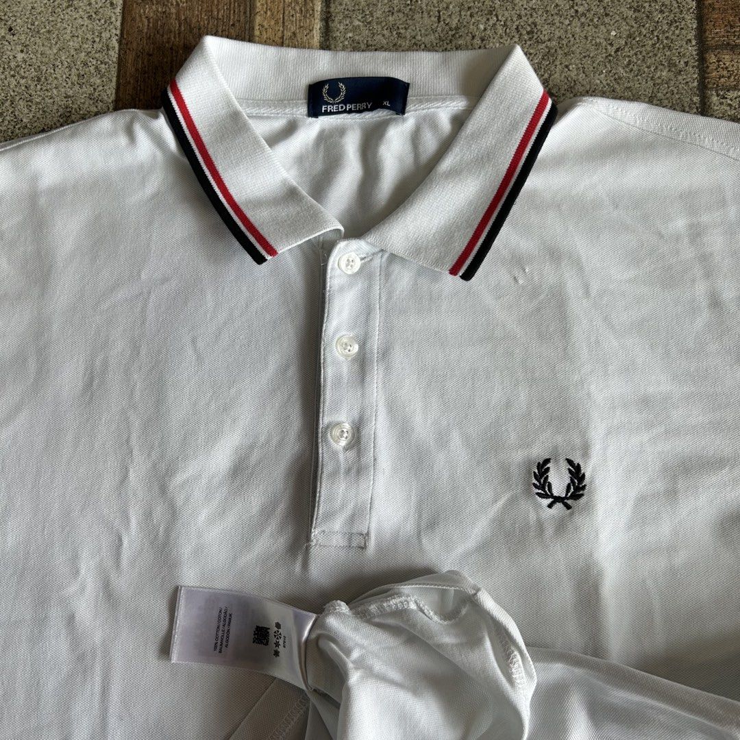 Fred Perry White Polo Shirt XL (Category: Tshirts & Polo Shirts ) located in Quezon. Submitted by webtothecloset (Listing ID 1440625213, Image 2). Description: - Classic white Fred Perry polo shirt - Size XL - Iconic embroidered laurel wreath logo on chest - Red and black striped trim on collar and sleeve cuffs - Button-up neckline.
