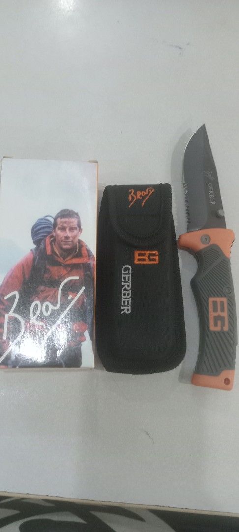 Gerber Bear Grylls Survival Knife with Sheath (Category: Hiking & Camping) located in Taytay. Submitted by joselaquino (Listing ID 1440604918, Image 1). Description: - Gerber Bear Grylls Survival Knife - Features a serrated blade - Black and orange handle - Includes a black nylon sheath with Bear Grylls logo - Comes with a Bear Grylls booklet - Ideal for outdoor adventures and collectors.