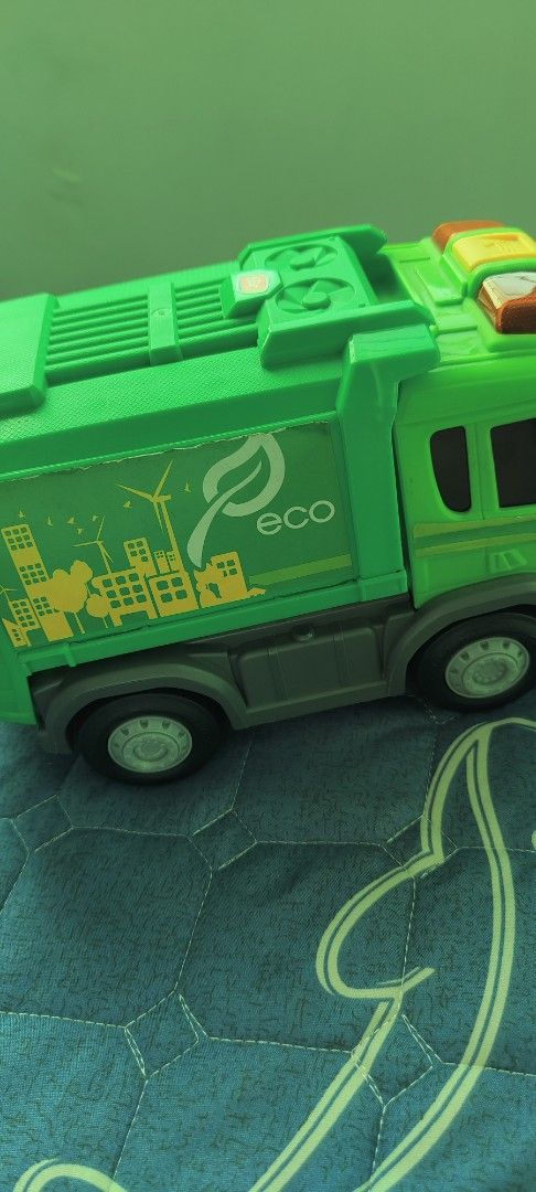Green Eco Garbage Truck Toy (Category: Kids Toys) located in Taguig. Submitted by sgaur909 (Listing ID 1440585197, Image 1). Description: - Green toy garbage truck with 'eco' and leaf logo. - Features a city skyline and wind turbine graphic. - Back bin lifts up and detaches for interactive play. - Ideal for children interested in trucks and recycling. - Combines fun with educational value about environmentalism..
