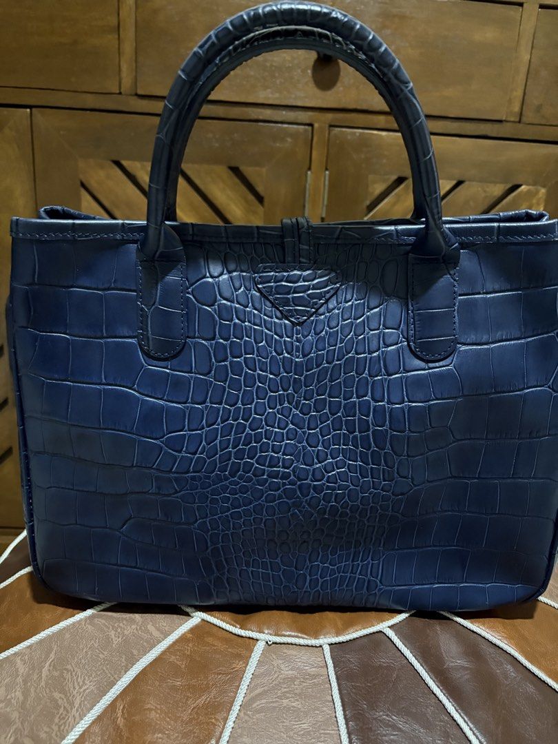 Longchamp Crocodile Embossed Leather Tote Bag Navy Blue (Category: Luxury Bags & Wallets) located in Paranaque City. Submitted by jnetpreloveditems (Listing ID 1440653702, Image 3). Description: - Navy blue Longchamp tote bag - Crocodile embossed leather exterior - Interior lining with butterfly print - Top handles for carrying - Front clasp closure - Spacious and versatile for everyday or special occasions.