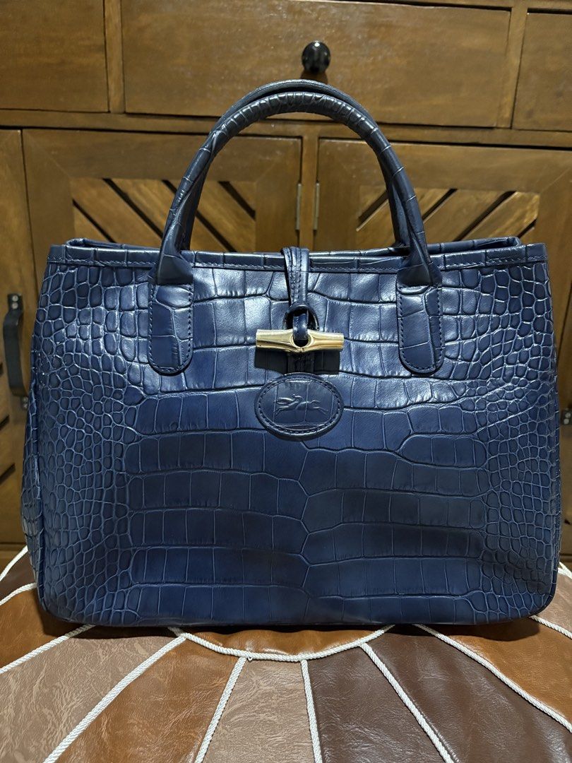 Longchamp Crocodile Embossed Leather Tote Bag Navy Blue (Category: Luxury Bags & Wallets) located in Paranaque City. Submitted by jnetpreloveditems (Listing ID 1440653702, Image 1). Description: - Navy blue Longchamp tote bag - Crocodile embossed leather exterior - Interior lining with butterfly print - Top handles for carrying - Front clasp closure - Spacious and versatile for everyday or special occasions.