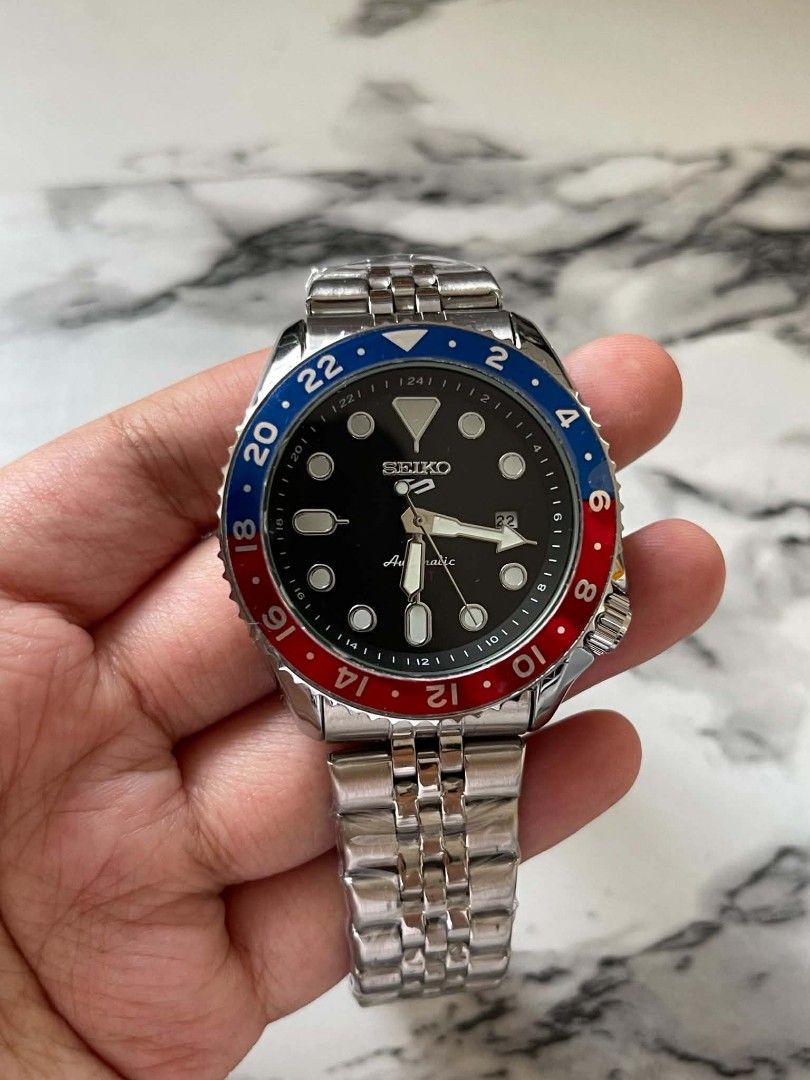 Seiko 5 GMT Pepsi Automatic Watch (Category: Men's Watches) located in Pasig City. Submitted by gheo0025 (Listing ID 1440723479, Image 2). Description: - Seiko 5 Automatic Watch - Classic Black Dial -Quartz movement - Red & Blue GMT Bezel for Dual Time Tracking - Durable Stainless Steel Jubilee Bracelet - Ideal for Travelers and Everyday Wear complete inclusion box and paper bag.