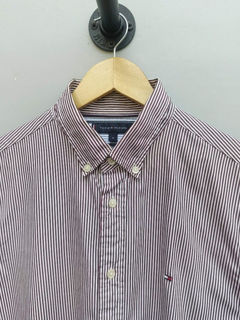 Tommy Hilfiger Men's Striped Button-Down Shirt - Size M (Category: Tshirts & Polo Shirts ) located in Taguig. Submitted by _theroom.ph (Listing ID 1440639996, Image 2). Description: - Brand: Tommy Hilfiger - Color: Burgundy and White Pinstripe - Style: Long-sleeved shirt - Material: 100% Cotton - Fit: Regular Fit - Features: Button-down collar, small embroidered logo on chest - Occasion: Casual or smart-casual wear.