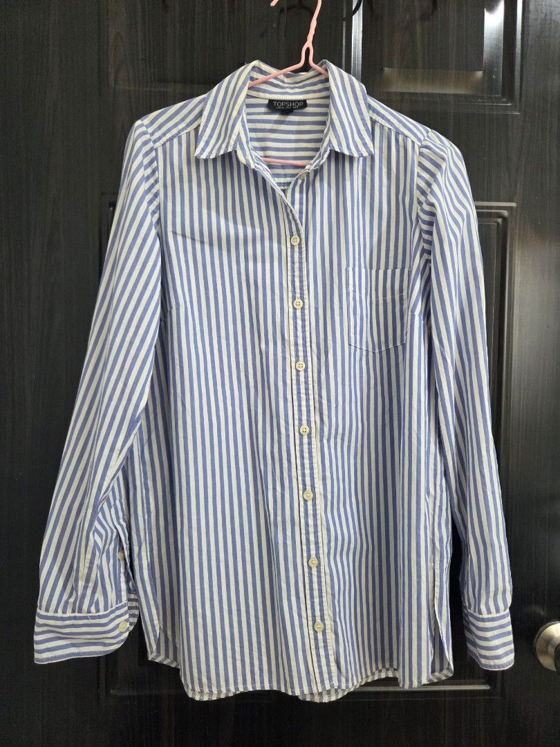 TOPSHOP Blue and White Striped Button-Down Shirt (Category: Shirts) located in Bacolod City. Submitted by maraline (Listing ID 1440673239, Image 1). Description: - Classic blue and white striped button-down shirt - Brand: TOPSHOP - Features a chest pocket - Button cuffs - Versatile for casual or smart-casual outfits - Made in Romania 079.