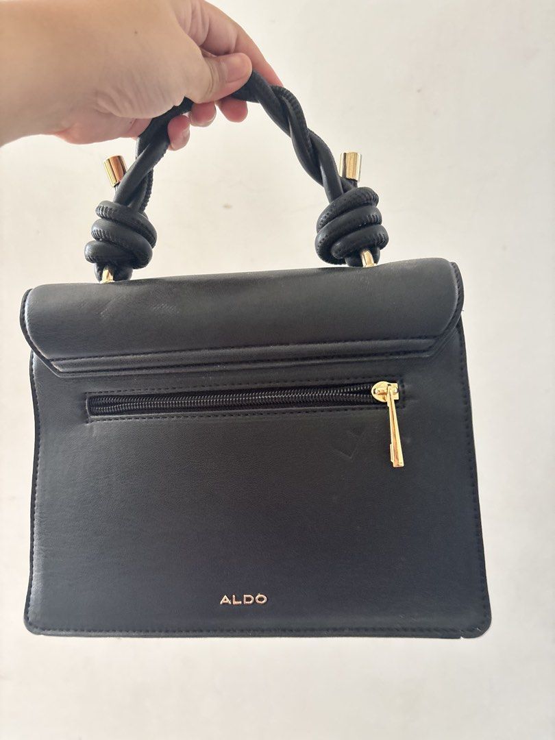 ALDO Black Handbag with Knot Handle (Category: Luxury Bags & Wallets) located in Bulacan. Submitted by mreyes21 (Listing ID 1435774542, Image 3). Description: - ALDO black handbag - Unique knot handle design - Gold accents - Flap closure with jewel detail - Back zippered pocket - Gold studs on front - Adds elegance to any outfit.