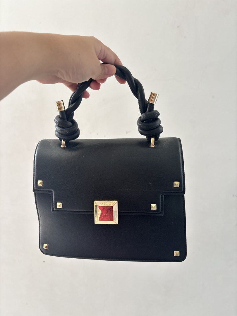 ALDO Black Handbag with Knot Handle (Category: Luxury Bags & Wallets) located in Bulacan. Submitted by mreyes21 (Listing ID 1435774542, Image 2). Description: - ALDO black handbag - Unique knot handle design - Gold accents - Flap closure with jewel detail - Back zippered pocket - Gold studs on front - Adds elegance to any outfit.