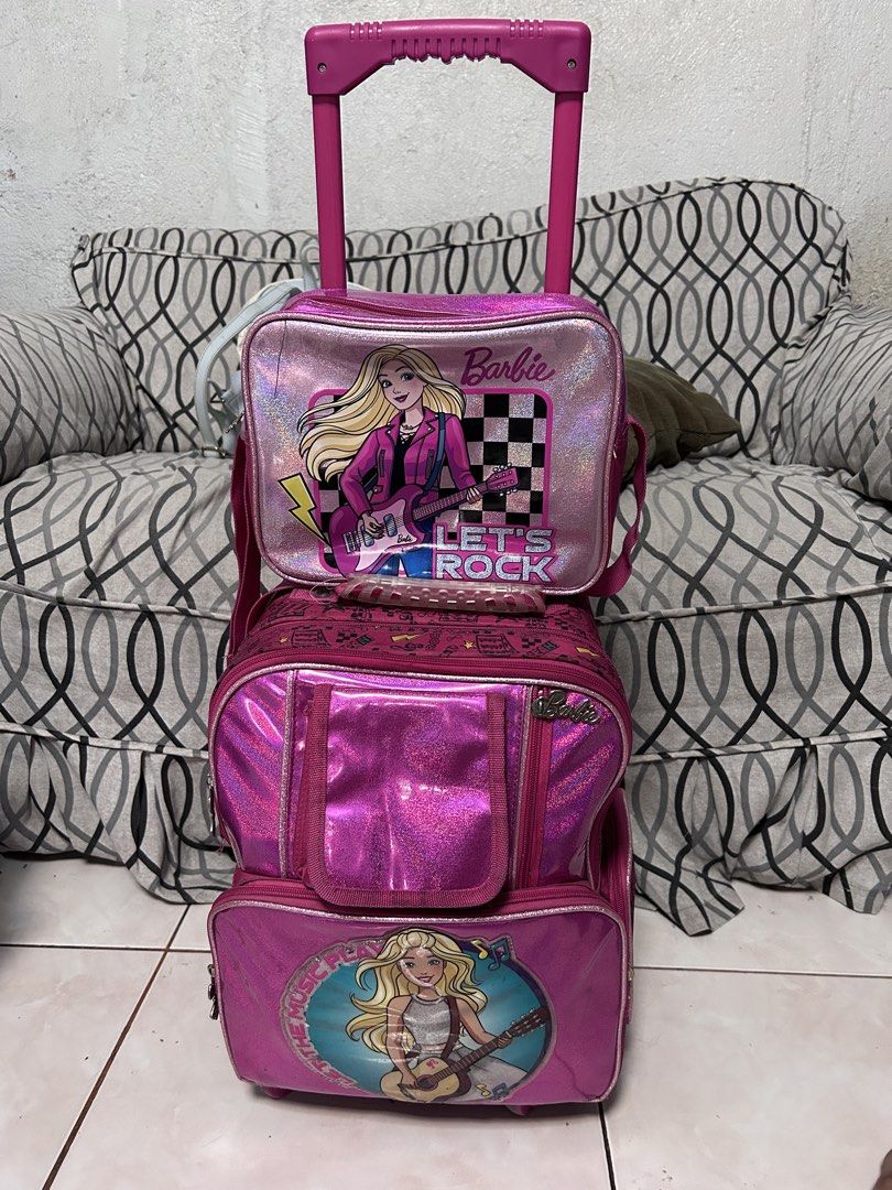 Barbie Rolling Backpack Set ( Trolley school bag) (Category: Babies & Kids Fashion) located in General Trias. Submitted by theosdeclutter (Listing ID 1435732479, Image 1). Description: - Barbie rolling backpack set - Features a vibrant pink design with Barbie graphics - Includes a main rolling backpack, a detachable smaller bag, and a front pocket - Rolling backpack has a retractable handle and wheels - Ideal for school or travel - Offers ample s