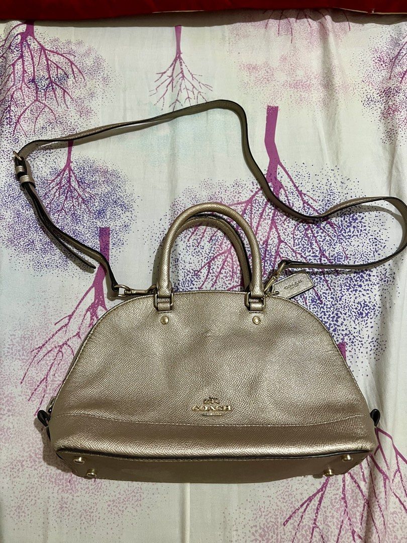 Coach Mini Sierra Satchel Handbag (Category: Luxury Bags & Wallets) located in Dagupan City. Submitted by casadebayongph (Listing ID 1435833636, Image 1). Description: Coach Mini Sierra Satchel handbag features a metallic gold finish. It has a top handle and a detachable shoulder strap. The bag has a zip closure and a Coach hangtag. The bag has a structured shape with a rounded base. With signs of usage sa handle and rubber linings. Ung creed niy