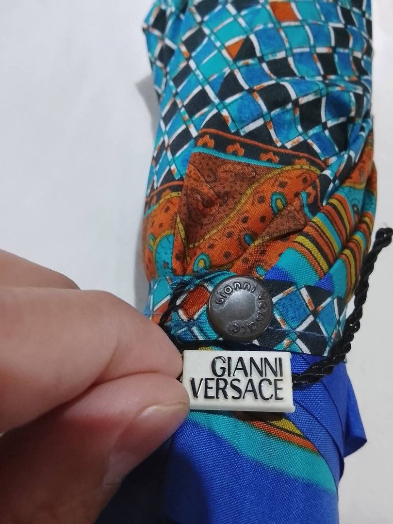 Gianni Versace Umbrella (Category: Umbrellas) located in Cabanatuan. Submitted by bagsyoulove (Listing ID 1435864723, Image 3). Description: - Authentic Gianni Versace umbrella - Features a blue, patterned canopy - Distinctive black triangular handle with silver ring - Versace branding visible on handle and button - Stylish and functional design.