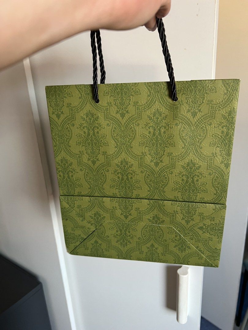 Gucci Paper Bag (Category: Luxury Bags & Wallets) located in Makati City. Submitted by marckyboy (Listing ID 1435813020, Image 2). Description: - Authentic Gucci paper bag - Features green damask pattern - Gucci logo on front - Black rope handles - Ideal for gifting or collecting - Stylish accessory.