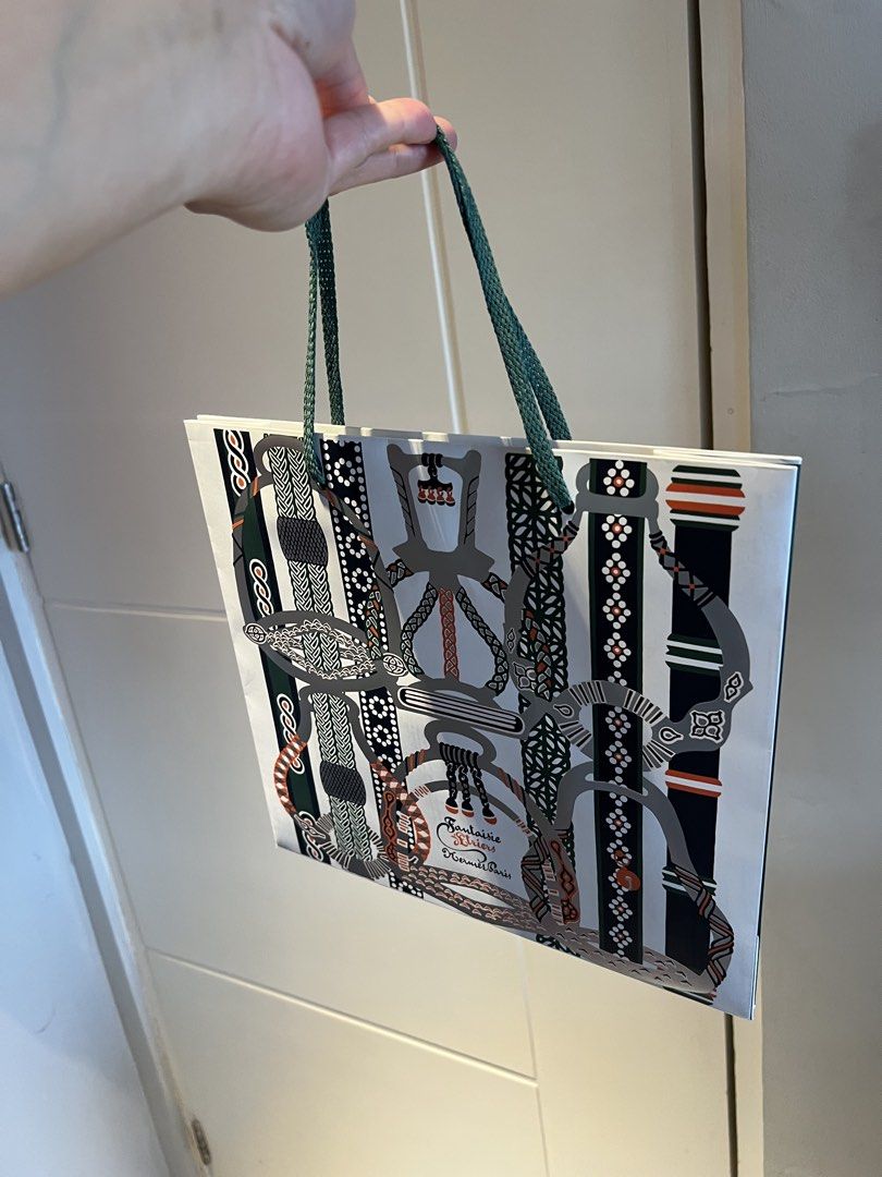 Hermes Paris Paper Bag (Category: Luxury Bags & Wallets) located in Makati City. Submitted by marckyboy (Listing ID 1435812056, Image 2). Description: - Authentic Hermes Paris paper bag. - Features a unique design. - Green handles. - White bag with a pattern in gray, green, and orange. - Perfect for gifting or collecting..