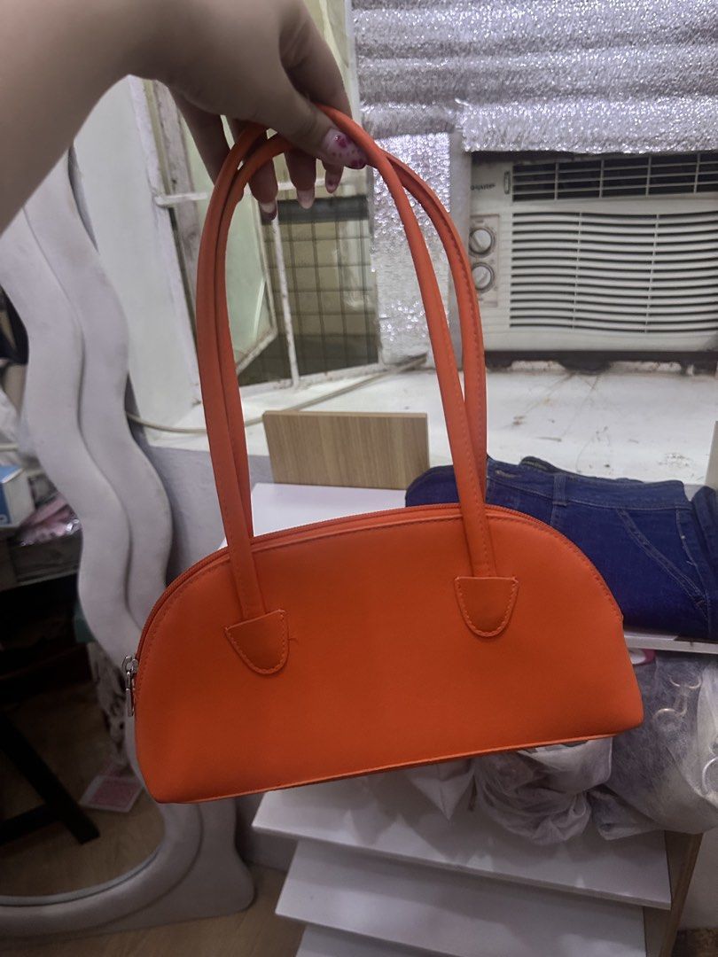 H&M Orange Shoulder Bag (Category: Shoulder Bags) located in General Trias. Submitted by treasuresbyp (Listing ID 1435876670, Image 2). Description: Bright orange shoulder bag from H&M. Features a half-moon shape with long handles. The interior is also orange. The bag has a zipper closure. The tag inside indicates the bag is made of polyester and polyurethane..