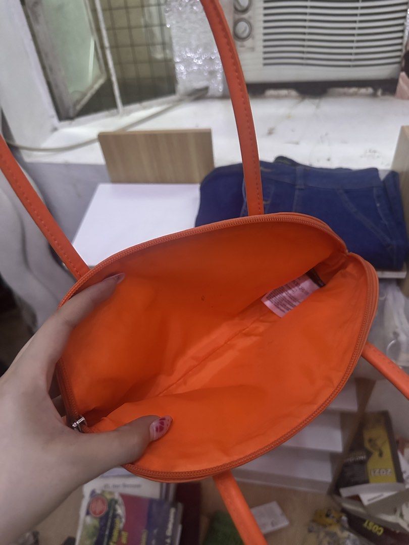 H&M Orange Shoulder Bag (Category: Shoulder Bags) located in General Trias. Submitted by treasuresbyp (Listing ID 1435876670, Image 3). Description: Bright orange shoulder bag from H&M. Features a half-moon shape with long handles. The interior is also orange. The bag has a zipper closure. The tag inside indicates the bag is made of polyester and polyurethane..