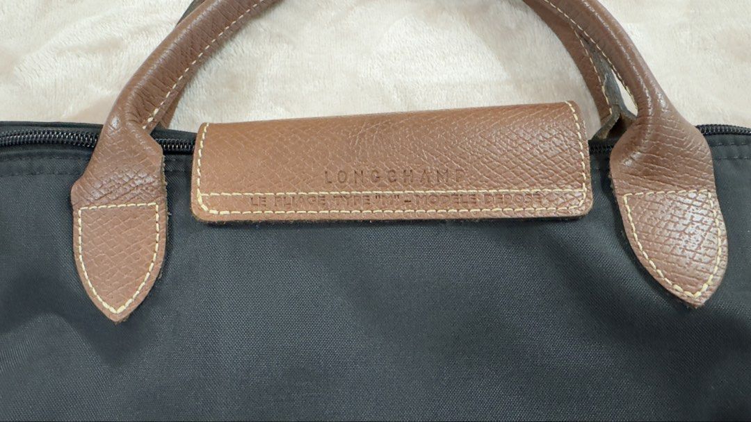 Longchamp Le Pliage Tote Bag - Black Medium Short Handle (Category: Luxury Bags & Wallets) located in Taguig. Submitted by rmsrnn (Listing ID 1435808273, Image 3). Description: - Classic Longchamp Le Pliage tote bag - Color: Black - Brown leather handles and flap - Gold-tone snap closure - Zipper closure with leather pull - Longchamp logo embossed on flap - Versatile everyday bag.