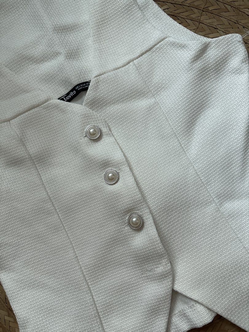 Lovito White Vest with Pearl Buttons (Category: Sleeveless) located in Manila. Submitted by _foryou (Listing ID 1435779625, Image 3). Description: - Lovito white vest - Textured fabric - V-neck design - Features three pearl-like buttons - Tailored fit - Slightly flared bottom - Sleeveless top.