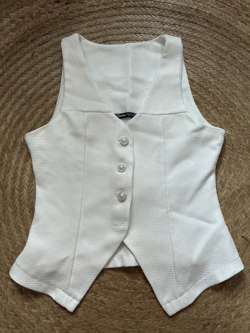Lovito White Vest with Pearl Buttons (Category: Sleeveless) located in Manila. Submitted by _foryou (Listing ID 1435779625, Image 1). Description: - Lovito white vest - Textured fabric - V-neck design - Features three pearl-like buttons - Tailored fit - Slightly flared bottom - Sleeveless top.