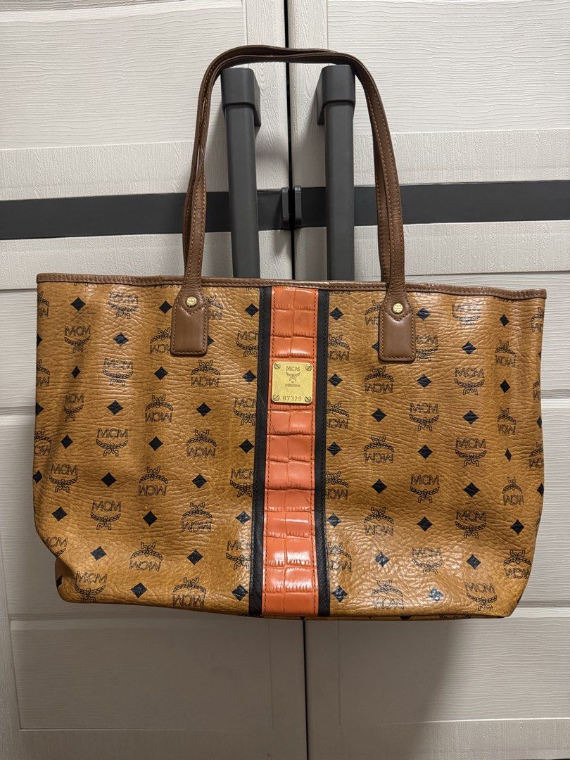MCM Visetos Coated Canvas Tote Bag (Category: Luxury Bags & Wallets) located in Caloocan City. Submitted by r_h_e_a10 (Listing ID 1435864390, Image 1). Description: - Authentic MCM tote bag - Iconic Visetos coated canvas with center stripe - Brown leather handles and trim - Gold-tone metal logo plate - Interior pocket - Includes certificate of authenticity - Light-colored interior lining.