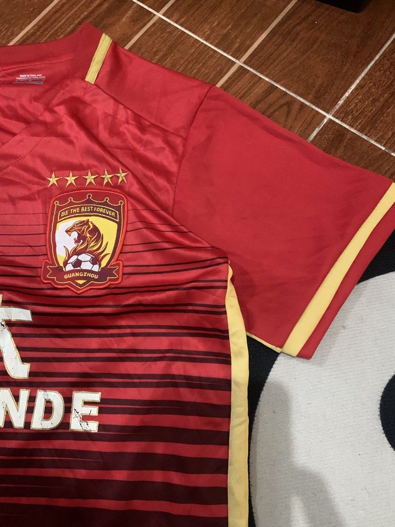 Nike Guangzhou Evergrande Jersey (Category: Activewear) located in Cavite. Submitted by secondhandco.archive552 (Listing ID 1435882230, Image 3). Description: NIKE EVERGRANDE 📌NO ISSUE 📌COLOR RATE: 9/10 📌CONDITION: 9/10 - Authentic Nike Guangzhou Evergrande jersey - Color: Red with yellow accents - Features team logo and "EVERGRANDE" print - V-neck design - Nike logo visible - Made in Thailand.