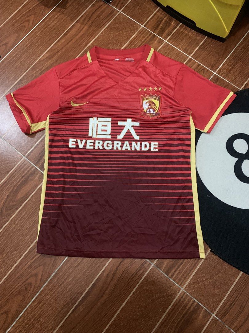 Nike Guangzhou Evergrande Jersey (Category: Activewear) located in Cavite. Submitted by secondhandco.archive552 (Listing ID 1435882230, Image 1). Description: NIKE EVERGRANDE 📌NO ISSUE 📌COLOR RATE: 9/10 📌CONDITION: 9/10 - Authentic Nike Guangzhou Evergrande jersey - Color: Red with yellow accents - Features team logo and "EVERGRANDE" print - V-neck design - Nike logo visible - Made in Thailand.