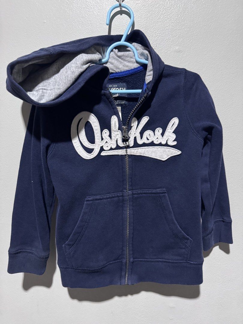 OshKosh 3T Zip-Up Hoodie (Category: Babies & Kids Fashion) located in General Trias. Submitted by lessleesell (Listing ID 1435882694, Image 1). Description: - OshKosh zip-up hoodie - Color: Navy blue - Size: 3T - Features: White "OshKosh" logo, hood with gray lining, front pocket - Made in Malaysia.