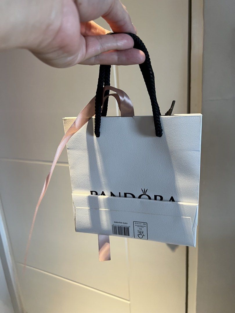 Pandora Gift Bag with Ribbon (Category: Luxury Bags & Wallets) located in Makati City. Submitted by marckyboy (Listing ID 1435815772, Image 2). Description: - Authentic Pandora gift bag - Features white exterior with Pandora logo and "UNFORGETTABLE MOMENTS" wording - Includes black rope handle and pink ribbon - Perfect for gifting Pandora jewelry.