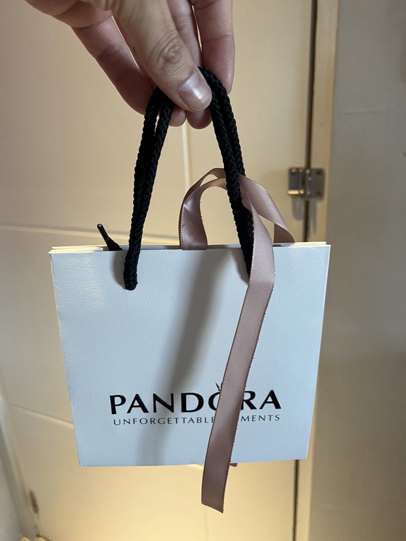 Pandora Gift Bag with Ribbon (Category: Luxury Bags & Wallets) located in Makati City. Submitted by marckyboy (Listing ID 1435815772, Image 1). Description: - Authentic Pandora gift bag - Features white exterior with Pandora logo and "UNFORGETTABLE MOMENTS" wording - Includes black rope handle and pink ribbon - Perfect for gifting Pandora jewelry.