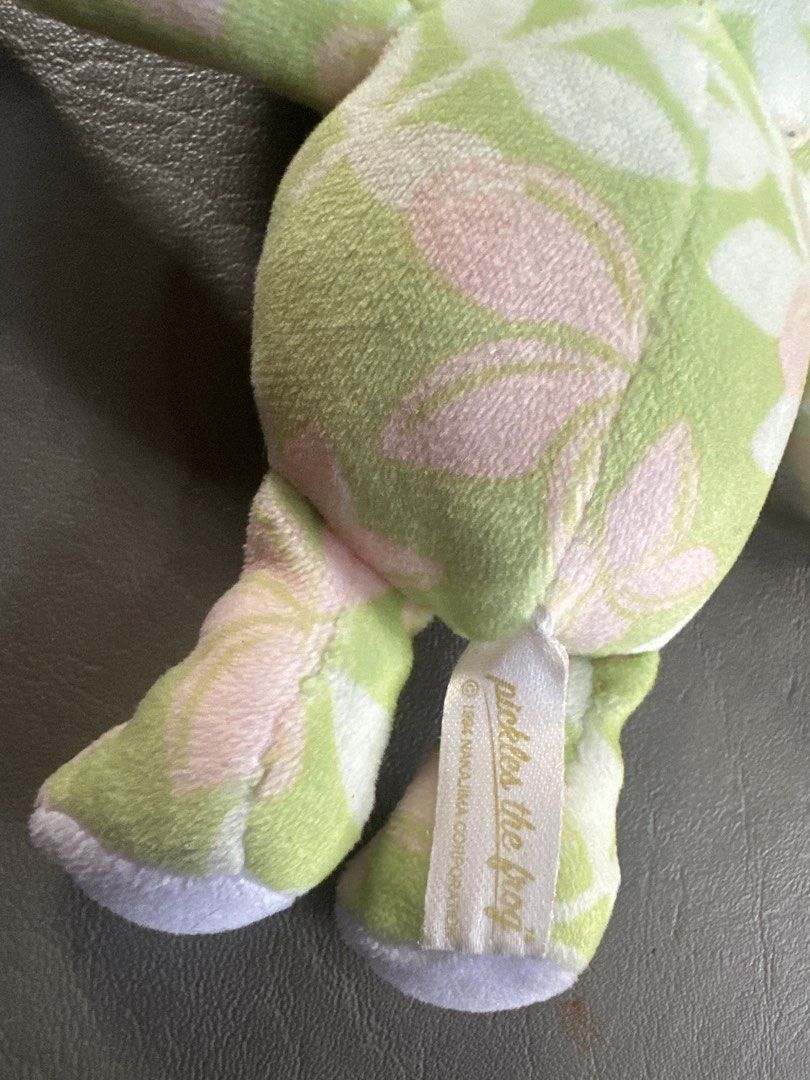 Pickles the Frog charms (Category: Plushies & Soft Toys) located in Cainta. Submitted by shopbyyna (Listing ID 1435783519, Image 3). Description: - Pickles the Frog plush toy - Green and pink floral pattern - Includes a beaded charm - Tag reads "Pickles the Frog" and "1984 Nakajima Corporation" - Smiling face and outstretched arms - Collectible item.