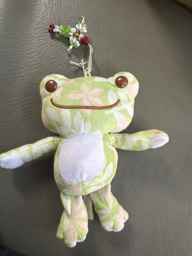 Pickles the Frog charms (Category: Plushies & Soft Toys) located in Cainta. Submitted by shopbyyna (Listing ID 1435783519, Image 1). Description: - Pickles the Frog plush toy - Green and pink floral pattern - Includes a beaded charm - Tag reads "Pickles the Frog" and "1984 Nakajima Corporation" - Smiling face and outstretched arms - Collectible item.