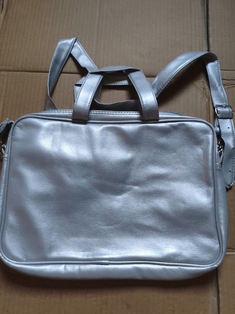 Silver Laptop Bag with Shoulder Strap (Category: Laptop Bags & Sleeves) located in Pasig City. Submitted by coolphoenix-29ac (Listing ID 1435818566, Image 1). Description: - Silver laptop bag - Includes shoulder strap and top handles - Main compartment and smaller interior pocket - Made of smooth, faux leather material - Rectangular shape - Adjustable shoulder strap.