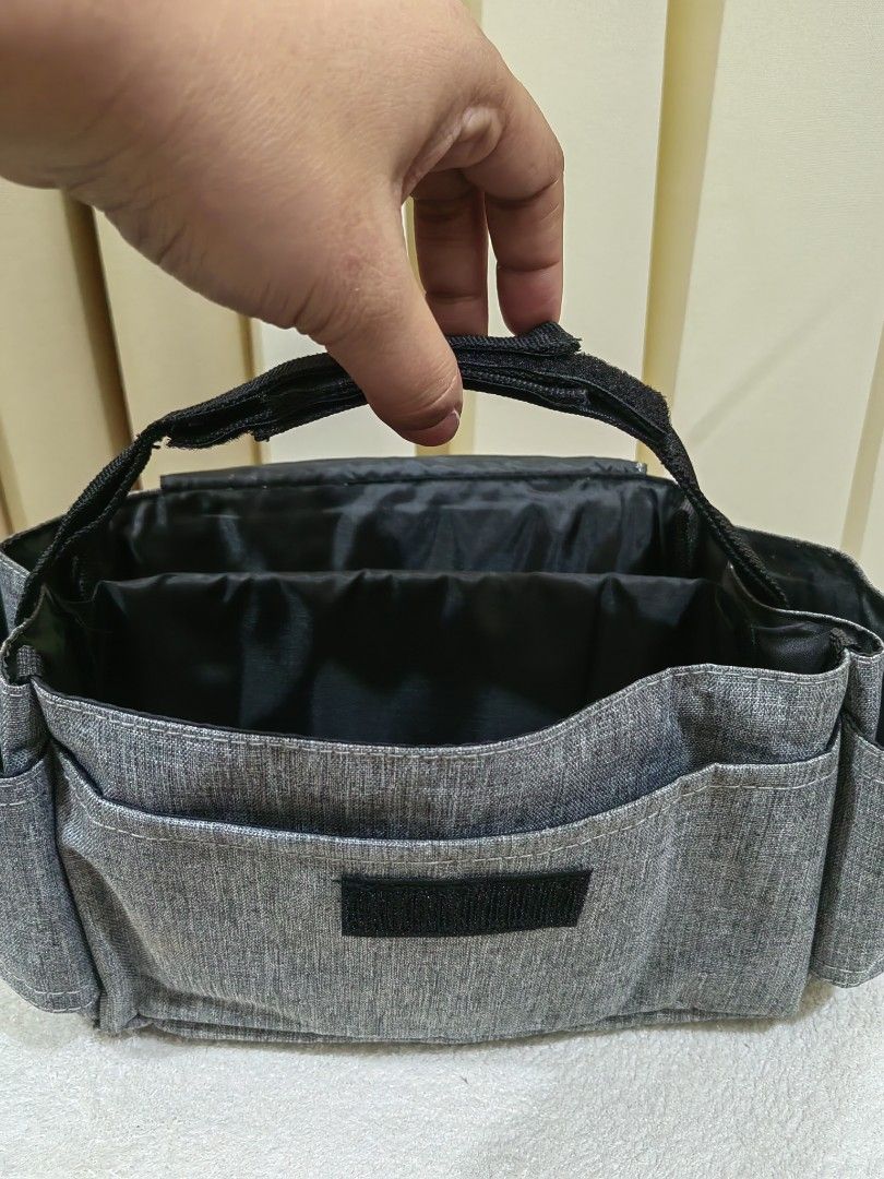 Stroller Organizer with Arrow Design (Category: Strollers) located in Makati City. Submitted by prelovedtreatedwithlove (Listing ID 1435831541, Image 3). Description: - Stroller organizer with multiple pockets for storage. - Features a stylish gray exterior. - Includes a flap with an arrow design. - Made from durable fabric. - Secure velcro closure. - Convenient carrying handle. - Interior with multiple compartments. -No issue A-101.