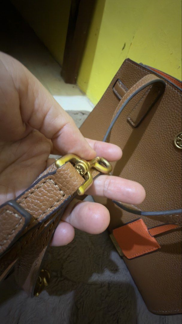 Tory Burch Brown Leather Handbag (Category: Luxury Bags & Wallets) located in Manila. Submitted by cpaspit (Listing ID 1435839946, Image 3). Description: - Tory Burch handbag - Brown leather exterior - Gold-tone zipper and hardware - Orange interior - Includes detachable strap - Features a cherry charm - Made in China.
