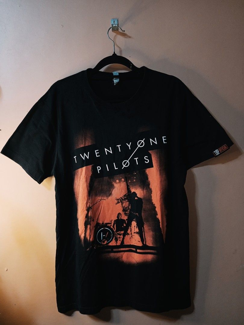 Twenty One Pilots Concert Tee (Category: Tshirts & Polo Shirts ) located in Victorias. Submitted by nekken620 (Listing ID 1435881515, Image 1). Description: Black Twenty One Pilots t-shirt featuring a concert graphic on the front. The band's name is printed in white across the top. The shirt has short sleeves and a crew neck. The tag on the sleeve indicates a brand logo. The shirt is hanging on a black hanger..