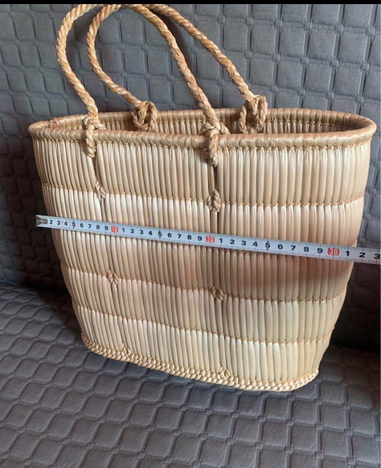 Woven Basket Bag (Category: Tote Bags) located in Makati City. Submitted by BRANDEDJAPANGOODS (Listing ID 1435749589, Image 2). Description: Handwoven basket bag with sturdy handles. Features a natural, light brown color. The bag has a rectangular shape with a woven design. The bag's dimensions are approximately 30cm in length and 20cm in height..