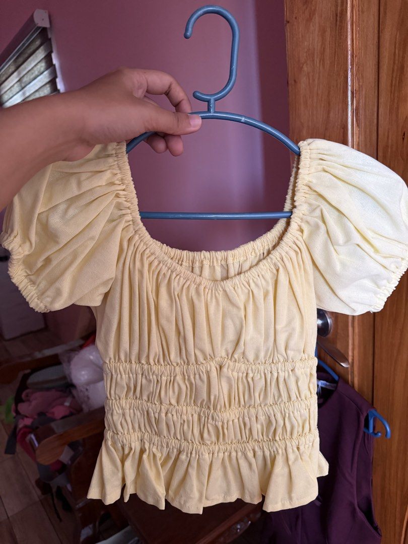 XS-S Yellow Puff Sleeve Top (Category: Blouses) located in Santa Rosa. Submitted by jstna (Listing ID 1435718844, Image 1). Description: - Square neckline - Puff sleeves - Ruched bodice - Ruffled hemline - Light yellow color - Displayed on a blue hanger.