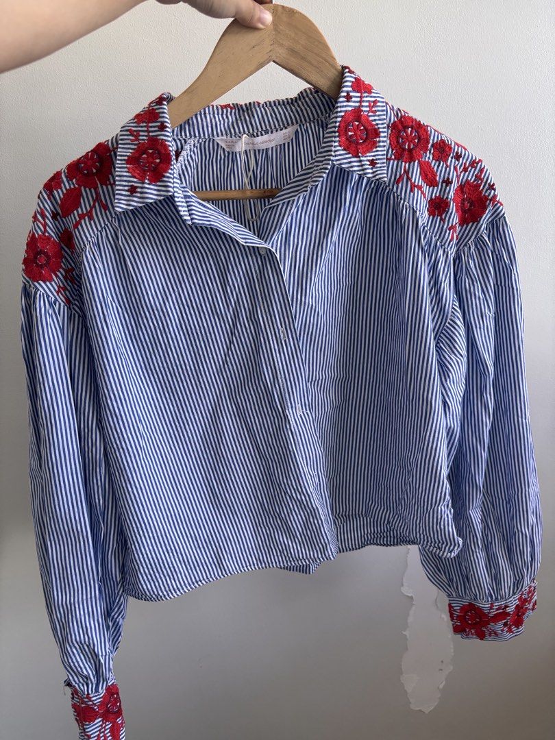 Zara Trafaluc Embroidered Striped Blouse (Category: Blouses) located in Manila. Submitted by taguigcloset (Listing ID 1435769178, Image 2). Description: - Zara Trafaluc blouse - Blue and white stripes - Red floral embroidery - Collared neckline - Long sleeves - Size S Rfs: decluttering honest issue: small tear on the sleeve - see photo.