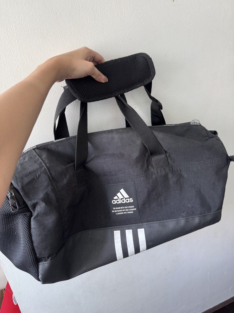 Adidas Black Duffel Bag with White Stripes (Category: Backpacks) located in Makati City. Submitted by danittt (Listing ID 1440809990, Image 2). Description: Adidas Black Duffel Bag with White Stripes - Classic black Adidas duffel bag - Features iconic white stripes at the bottom - Multiple Adidas logos printed throughout - Includes top handles for easy carrying - Detachable padded shoulder strap for comfort - Ideal for gym sessions or travel geta