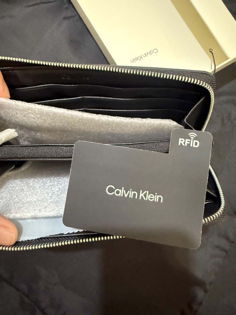 Authentic Calvin Klein Black Leather Zip Around Wristlet Wallet (Category: Wallets & Card holders) located in Manila. Submitted by deoksun (Listing ID 1440816542, Image 3). Description: - Authentic Black Calvin Klein wallet - Detachable wrist strap - Multiple card slots and compartments - Built-in RFID blocking card - Comes in original box - Perfect for organizing your essentials NEGOTIABLE .