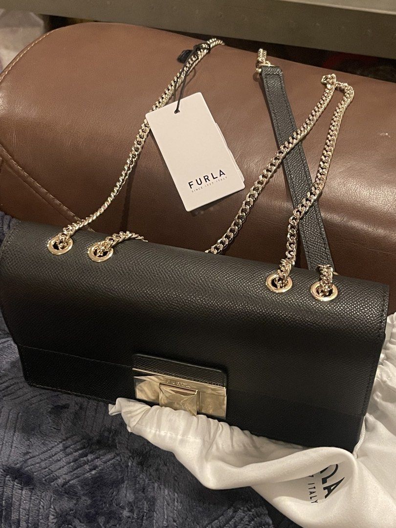 Furla Venere Convertible Bag (Category: Luxury Bags & Wallets) located in Muntinlupa City. Submitted by kcferre (Listing ID 1436768805, Image 2). Description: - Authentic Furla Venere bag - Black leather exterior - Gold-tone chain strap and clasp - Includes original dust bag and tags - Rectangular shape with flap closure - Furla logo visible.