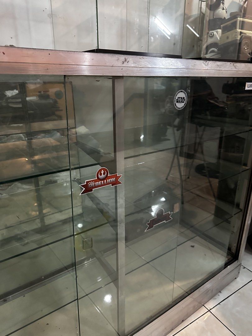 Glass Display Cabinet with Metal Frame (Category: Shelves, Cabinets & Racks) located in Marikina City. Submitted by mekanikko2026 (Listing ID 1440945512, Image 2). Description: - Glass display cabinet with sturdy metal frame - Features sliding glass doors for easy access - Multiple shelves for ample storage or display space - Decorated with cool Star Wars stickers on the glass - Perfect for shops, collectors, or home display - Pickup only.