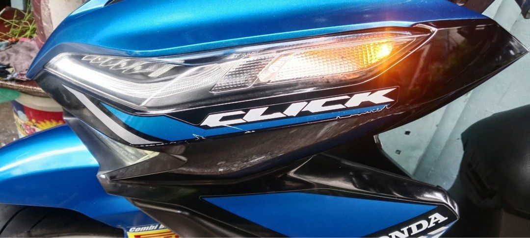 Honda Click 125i Motorcycle Blue (Category: Motorbikes for Sale) located in Quezon City. Submitted by jammatriano (Listing ID 1440863866, Image 3). Description: Honda Click 125i scooter in a vibrant blue. Has a sleek design with sharp headlights. The seat is covered with a black seat cover. White rims add a nice contrast. Ready for the road. Great for city commuting..