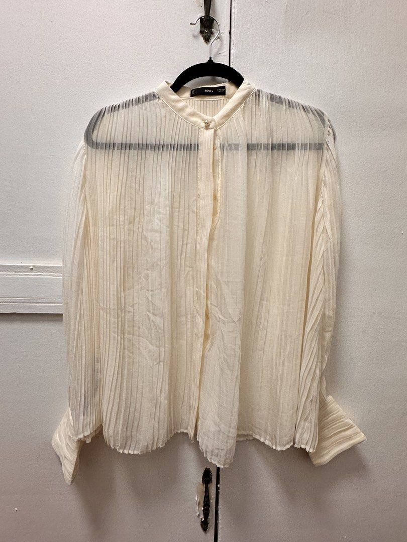 MNG Cream Pleated Long Sleeve Button Up Blouse (Category: Blouses) located in Manila. Submitted by shannenvel63434 (Listing ID 1440898977, Image 1). Description: - Cream colored MNG blouse - Long sleeves with pleated details - Button up front with a unique collar button - Sheer fabric with vertical pleats all over - Versatile for dressing up or down - Perfect for layering.