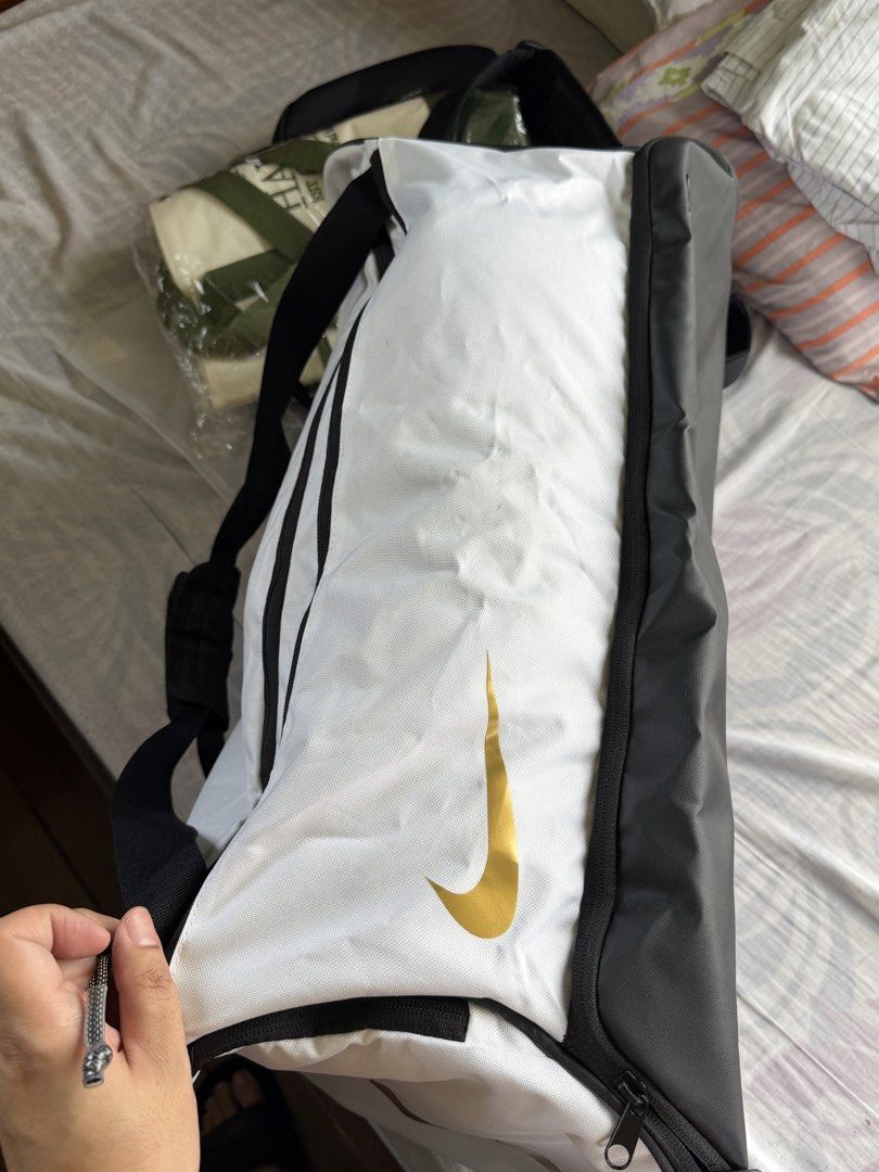 Nike hoops elite training duffle bag 57L (Category: Sling Bags) located in Bulacan. Submitted by elihoh (Listing ID 1440768139, Image 2). Description: - White Nike duffel bag - Black accents and gold Nike swoosh - Main compartment for storage - Convenient side pockets - Adjustable shoulder strap included - Ideal for gym sessions or travel - Spacious interior.
