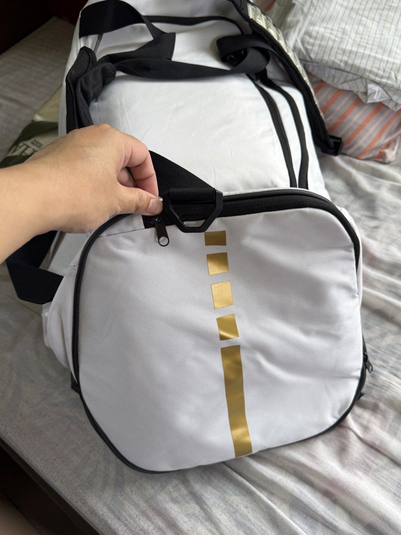 Nike hoops elite training duffle bag 57L (Category: Sling Bags) located in Bulacan. Submitted by elihoh (Listing ID 1440768139, Image 3). Description: - White Nike duffel bag - Black accents and gold Nike swoosh - Main compartment for storage - Convenient side pockets - Adjustable shoulder strap included - Ideal for gym sessions or travel - Spacious interior.