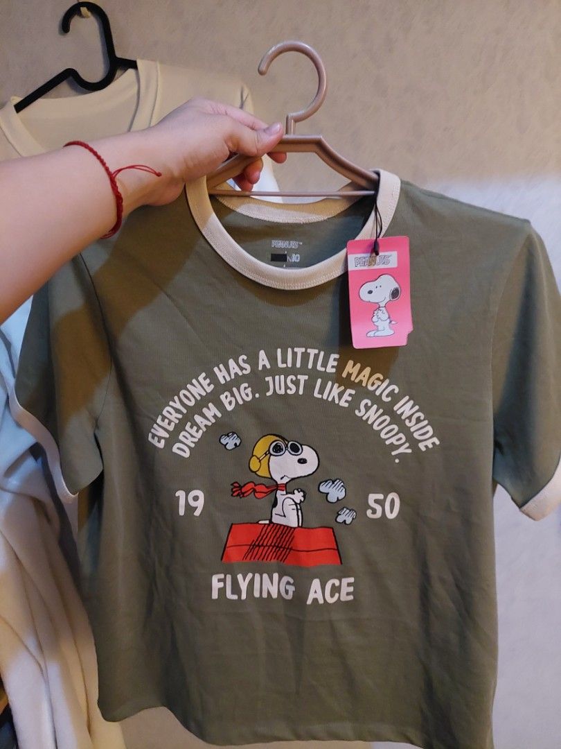 Peanuts Snoopy Flying Ace Graphic T-Shirt (Category: Shirts) located in Manila. Submitted by lykadeniese (Listing ID 1440910391, Image 1). Description: - Olive green t-shirt with a cute Snoopy graphic. - Features the inspiring quote: 'Everyone has a little magic inside... Just like Snoopy'. - Also includes '19 50 Flying Ace' print. - Contrasting trim on the collar and sleeves adds a stylish touch..
