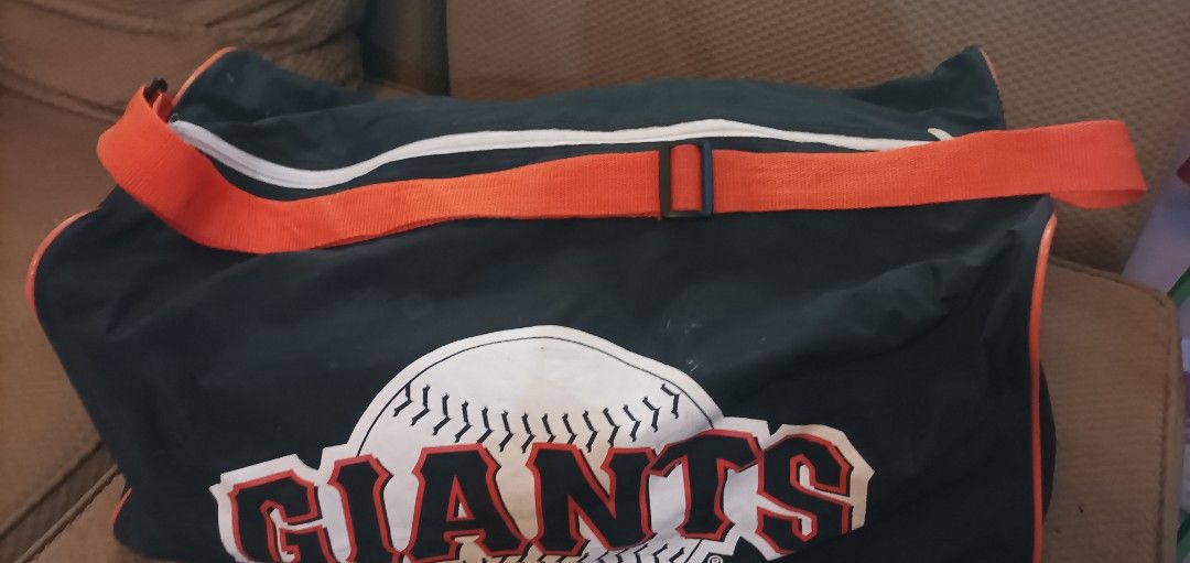 San Francisco Giants MBNA America Gym Duffel Bag (Category: Backpacks) located in Lucena. Submitted by miles.miles1 (Listing ID 1440793657, Image 2). Description: - Black duffel bag with vibrant orange trim and strap. - Features the iconic San Francisco Giants logo on the front and back sides. - Showcases MBNA America branding on the sides. - Generous size: 21" x 10" - ideal for gym essentials or weekend getaways. - Perfect for displaying your te