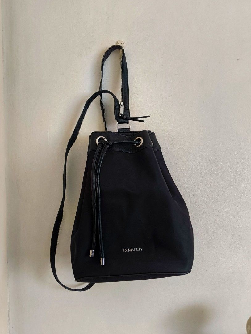 Calvin Klein Black Drawstring Bucket Backpack (Category: Backpacks) located in Quezon City. Submitted by afteruse (Listing ID 1440973861, Image 1). Description: - Bought by relatives in the US as a gift - Convertible strap at the back - Used 3x lang 🥲 - PU leather was already flaking on 1st use 😭 wtf - Sayang talaga because the hardware and the nylon body is durable and of good quality. 🥲🥲🥲 yung pu lang talaga 🥲 Similar listing on Poshmark: