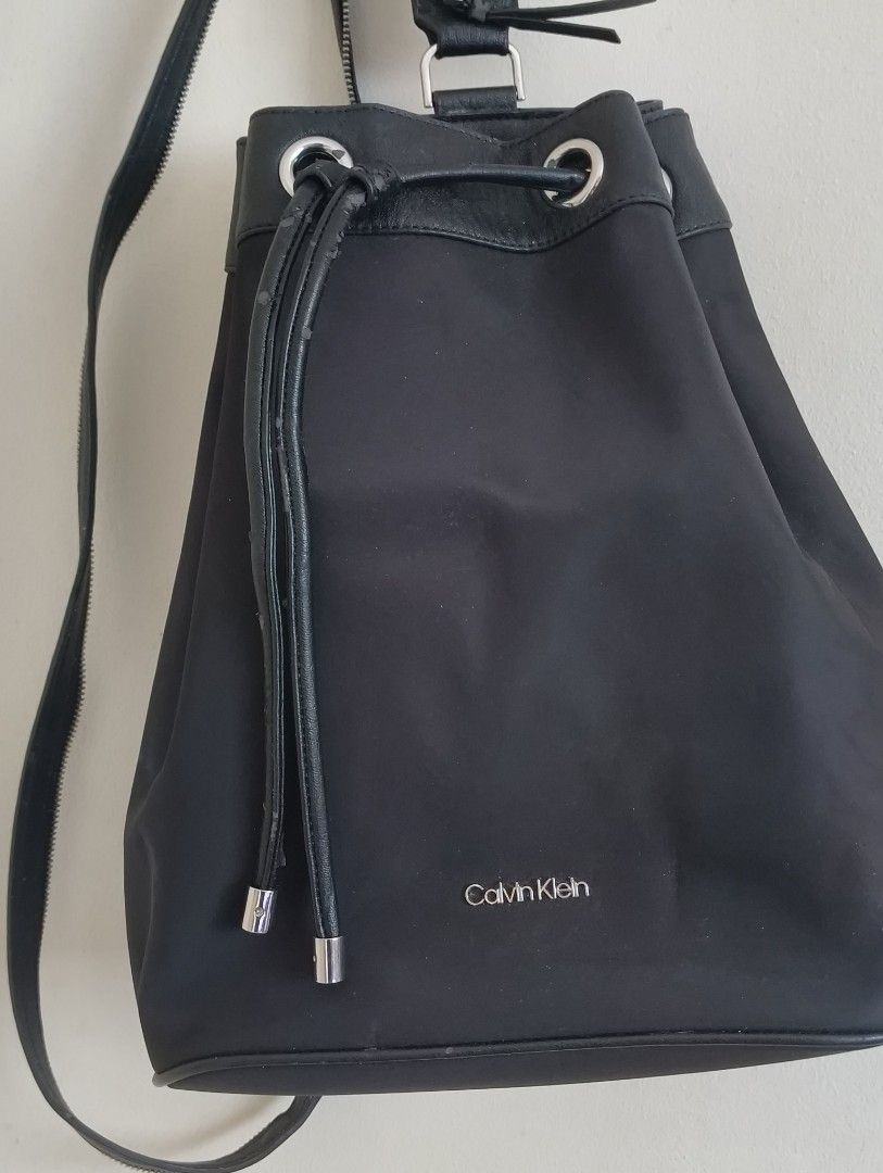 Calvin Klein Black Drawstring Bucket Backpack (Category: Backpacks) located in Quezon City. Submitted by afteruse (Listing ID 1440973861, Image 2). Description: - Bought by relatives in the US as a gift - Convertible strap at the back - Used 3x lang 🥲 - PU leather was already flaking on 1st use 😭 wtf - Sayang talaga because the hardware and the nylon body is durable and of good quality. 🥲🥲🥲 yung pu lang talaga 🥲 Similar listing on Poshmark: